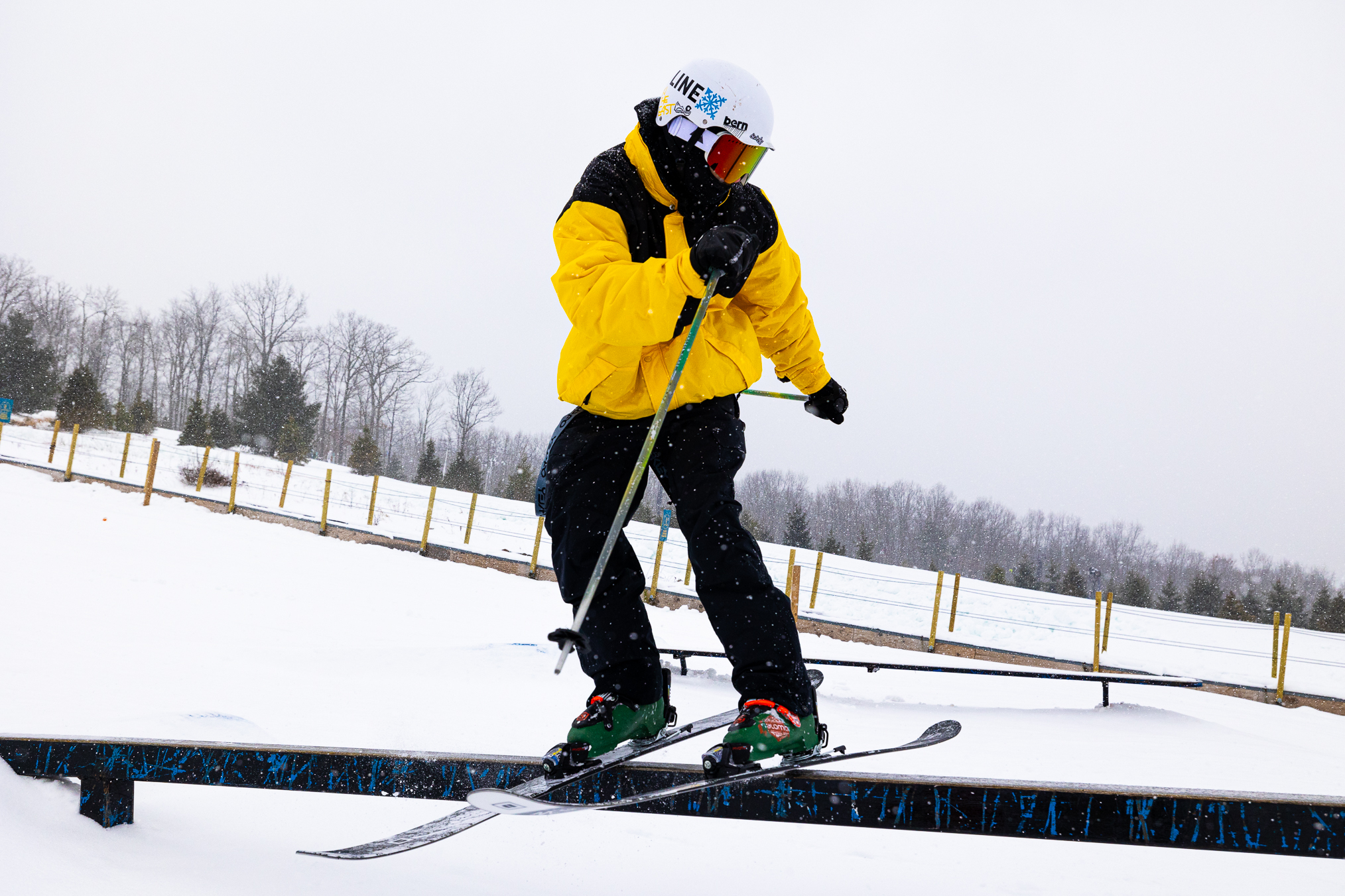 Skier in a yellow jacket sliding a terrain park rail at Montage Mountain